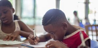 boy writing on printer paper near girl