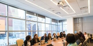 group of people sitting beside rectangular wooden table with laptops