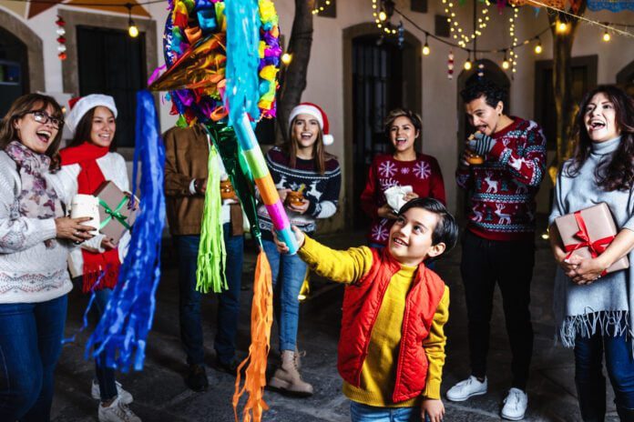 Hispanic child boy with Mexican family breaking a pinata at traditional posada party for Christmas in Mexico Latin America Las Posadas, the Latin American holiday celebrating the journey Joseph and Mary took before Jesus' birth, is celebrated Dec. 16-24 with food and drinks, music and a piñata. (Photo/Getty Images)