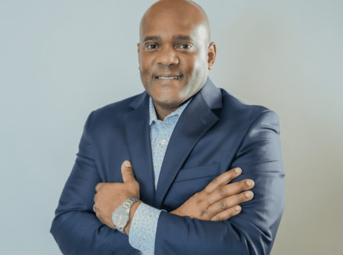 Robert Shegog Headshot Man in a suit with arms folded.