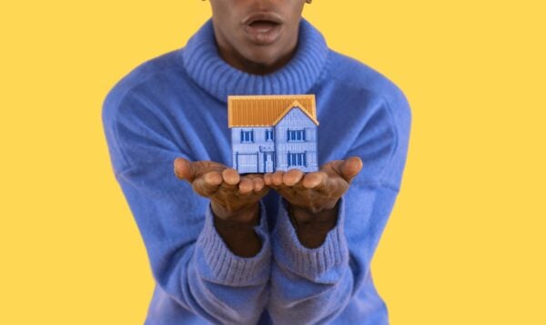 Big house in hand on blue background. trying to find an affordable house to buy or rent concept
