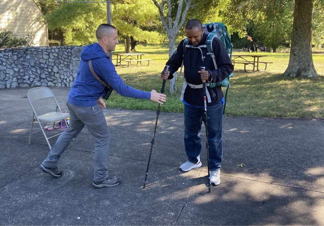 staffer helps refugee prepare for hiking
