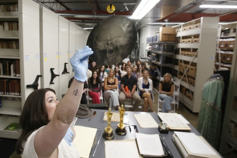 Emily Rapoza, director of the Songbook Library & Archives, displays historical items to a visiting student group.