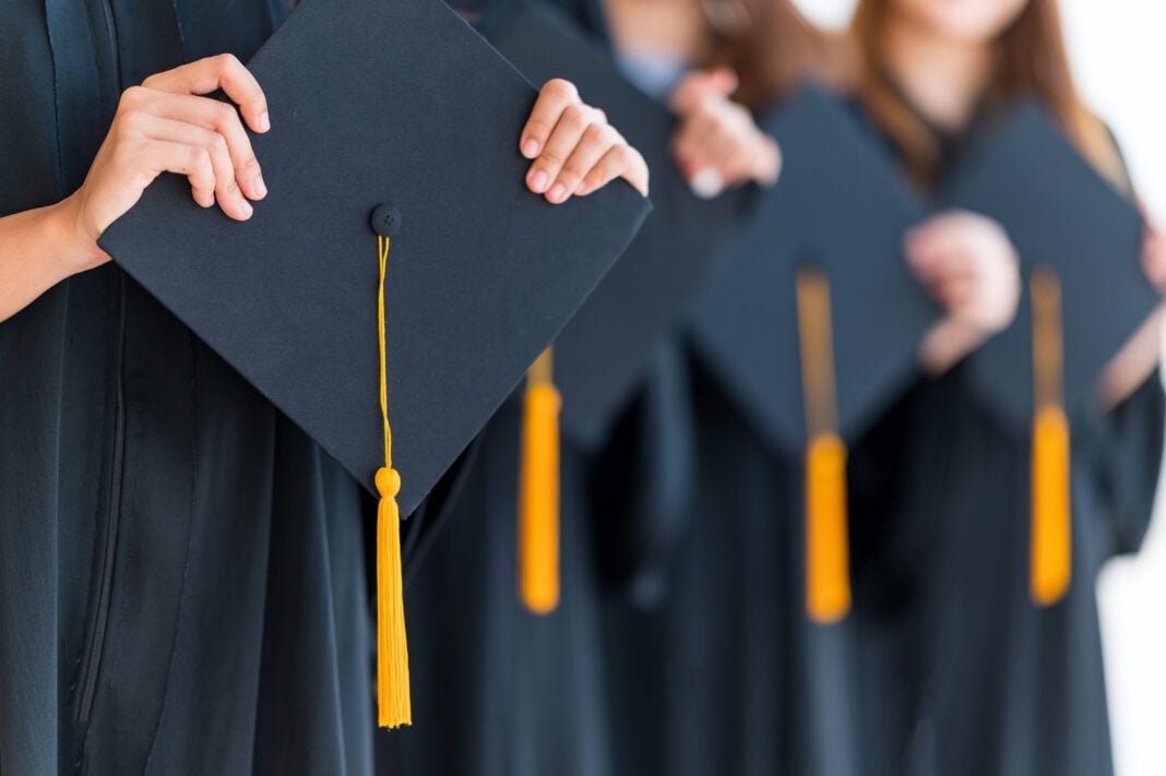 Close up group of graduates holding a hat At the graduation ceremony at the university Graduate caps and gowns