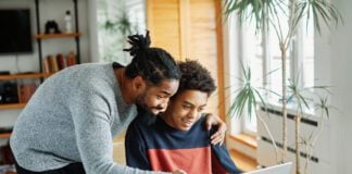 Father and son doing homework with laptop at home. Father and teenage son using laptop. Boy and dad sitting at home working with notebook