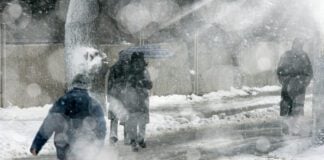 people walking on city street under snowing