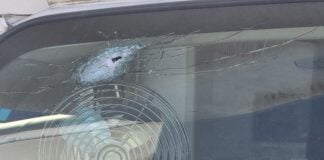 a bullet hole in the front windshieild of the Dirty Dozen Hunting and Fishing Club's commercial bus.