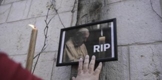A person touching a phjoto of Pope Francis.