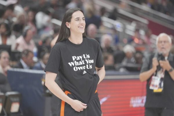 WNBA CBA Caitlin Clark wearing Pay Us What You Owe Us protest shirt during WNBA All Star in Indianapolis in July of 2025.