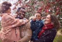 Parents Carrying Children As Family Enjoy Fall Or Winter Walk In Countryside In Snow