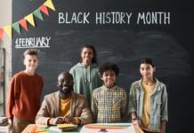2026 Black History Month Student Poetry & Essay Contest Portrait of African American teacher smiling at camera together with his children while they standing against the blackboard
